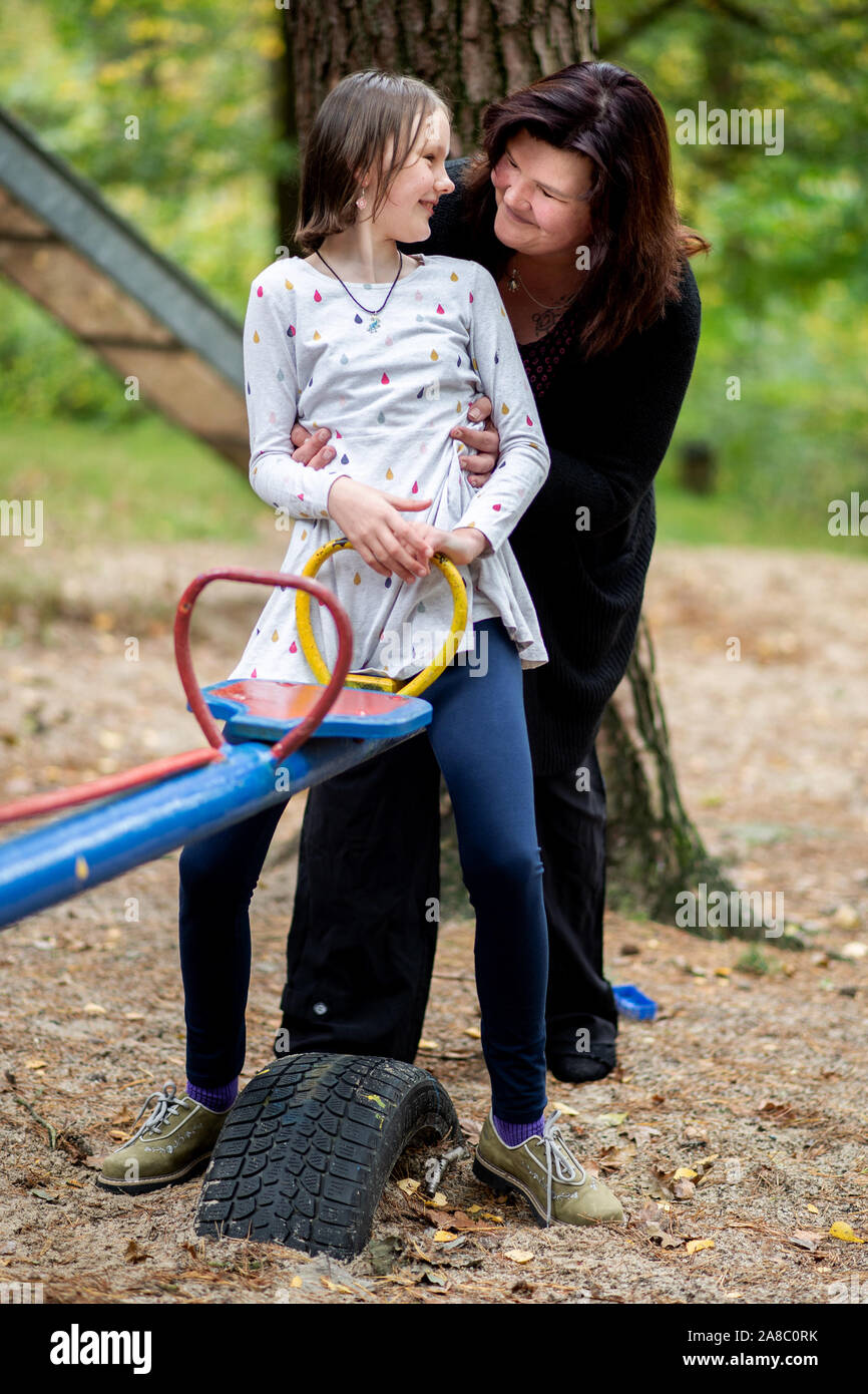14 October 2019, Lower Saxony, Löningen: Kathrin Schenk and her daughter Tabea are sitting on a seesaw on a playground. When her daughter Tabea starts blinking or the noise of her siblings suddenly becomes too much for her, Kathrin Schenk knows: 'A migraine attack is on the way. According to estimates by the German Migraine and Headache Society (DMKG), every tenth child has migraine. Photo: Hauke-Christian Dittrich/dpa Stock Photo