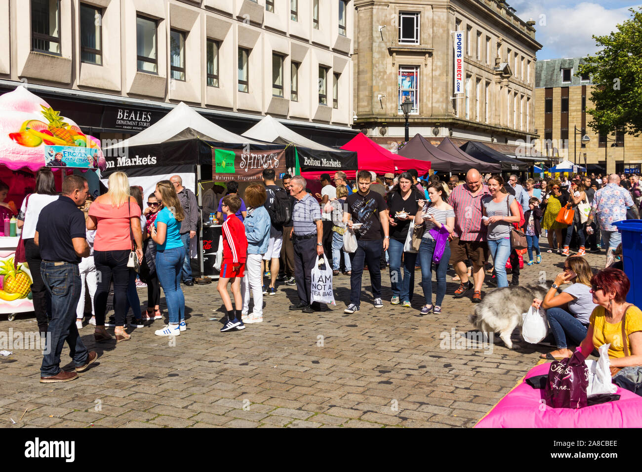 Visitors walking by various takeaway savoury and sweet food stalls on Le Mans Crescent at the Bolton Food Festival 2017 Stock Photo