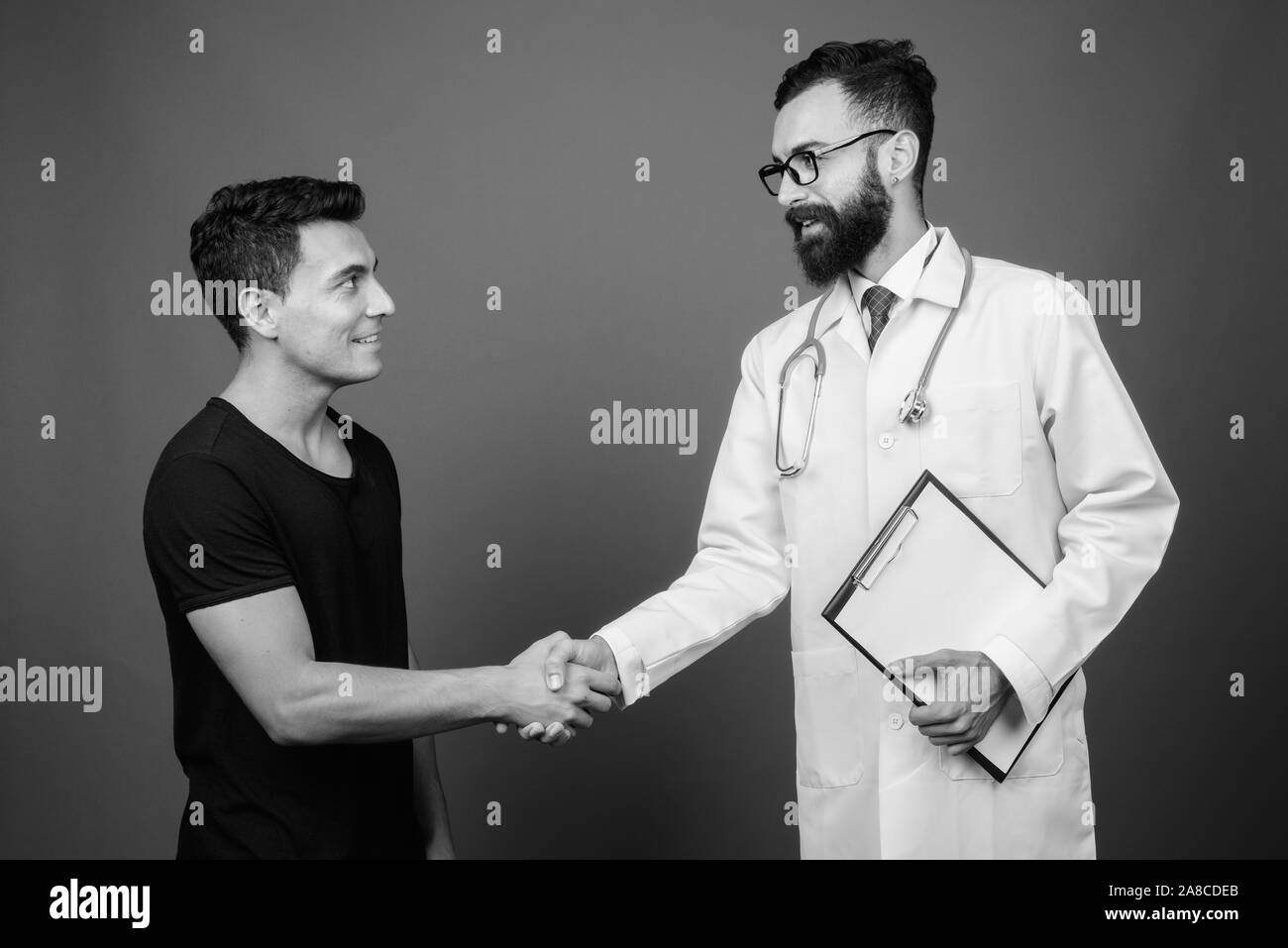 Young bearded Persian man doctor with young Hispanic man patient Stock Photo