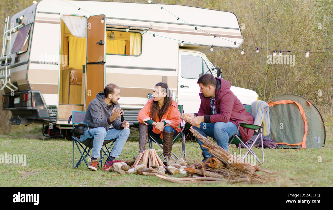 Man Telling A Story To His Friends Sitting On Camping Chairs In