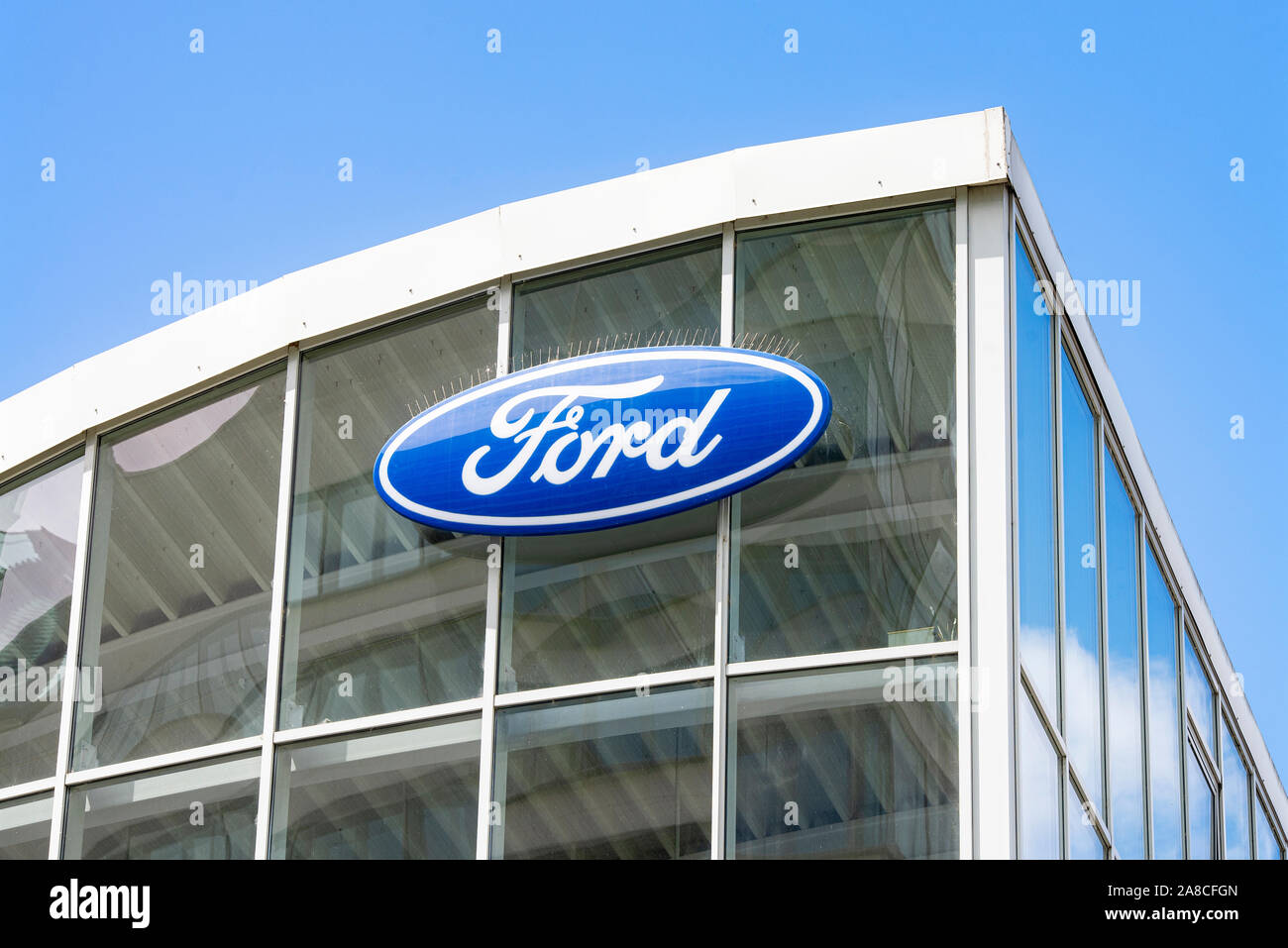 Ford logo on the glass facade of a car dealership Stock Photo
