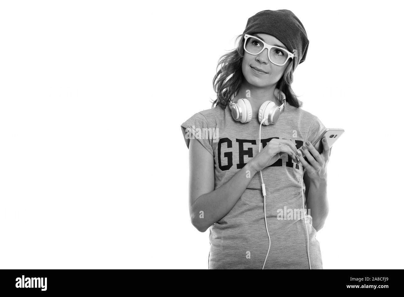 Studio shot of geek girl holding mobile phone while thinking with