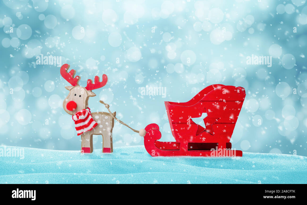 Santa Claus deer and empty sleigh in snow. Cute wooden toy. Copy space above. Stock Photo