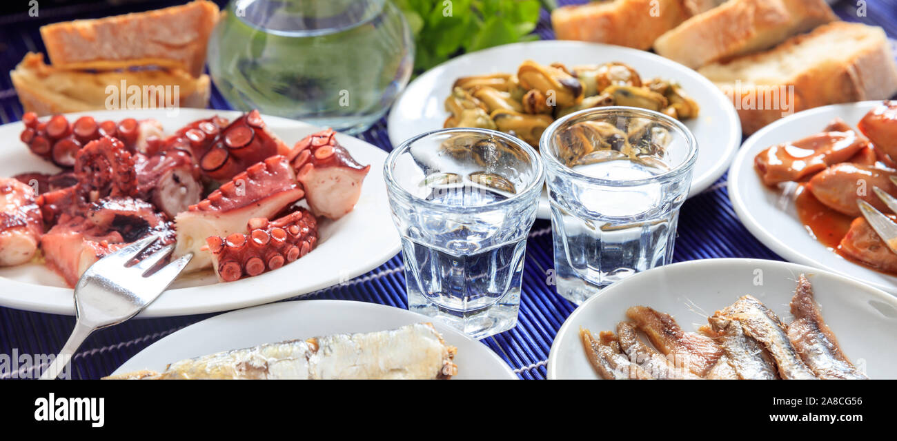 Raki, ouzo alcohol banner, Two glasses and seafood meze appetizers background, closeup view Stock Photo