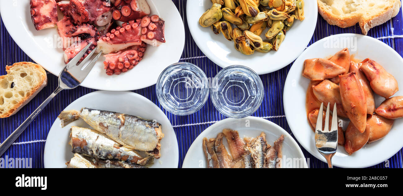 Raki, ouzo alcohol banner, Two glasses and seafood meze appetizers background, top view Stock Photo
