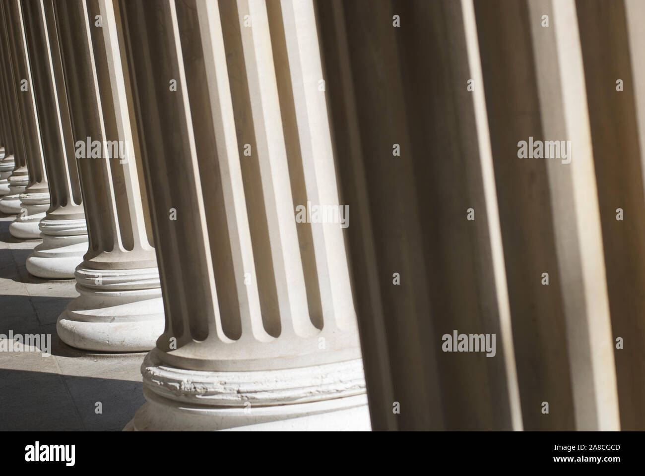 Dramatic sunlit down a colonnade of fluted columns with shadowy architectural texture Stock Photo