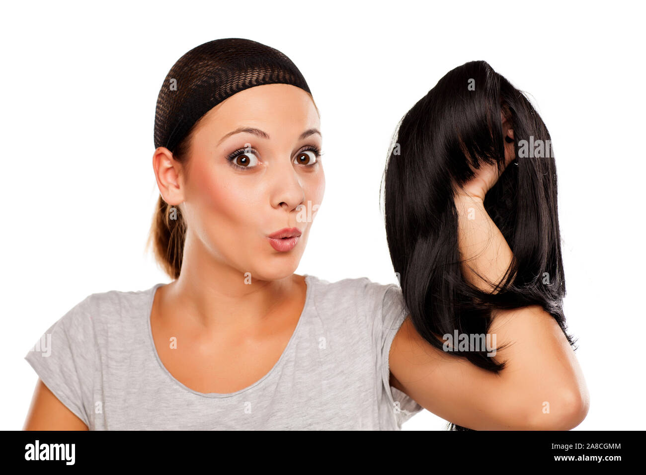 young woman with a wig cap on her head holding a wig in hand Stock