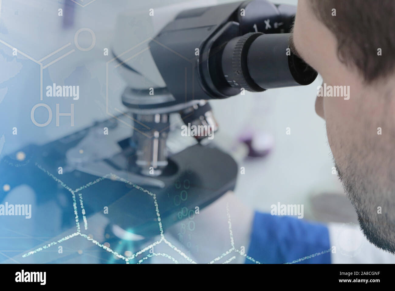 Young male male scientist looking through a microscope in a laboratory ...