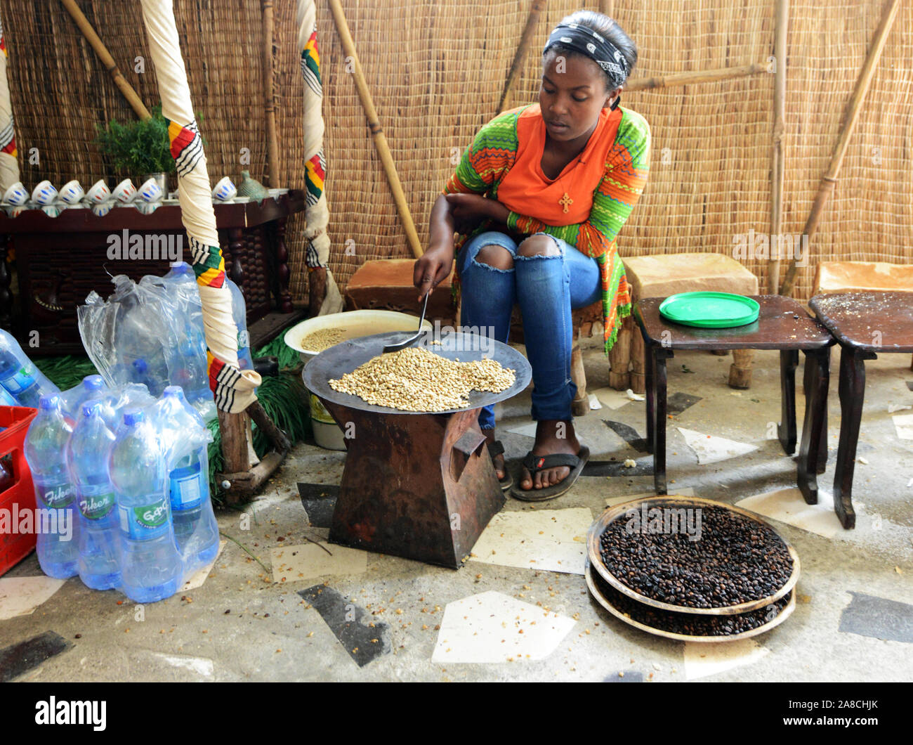 A young Ethiopian woman roasting coffee beans in preparation of