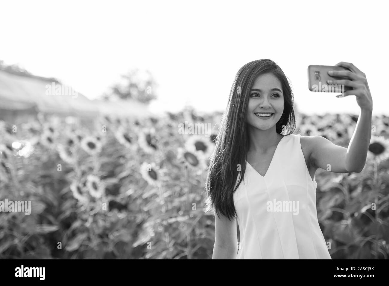 Young happy Asian woman smiling while taking selfie picture with mobile ...