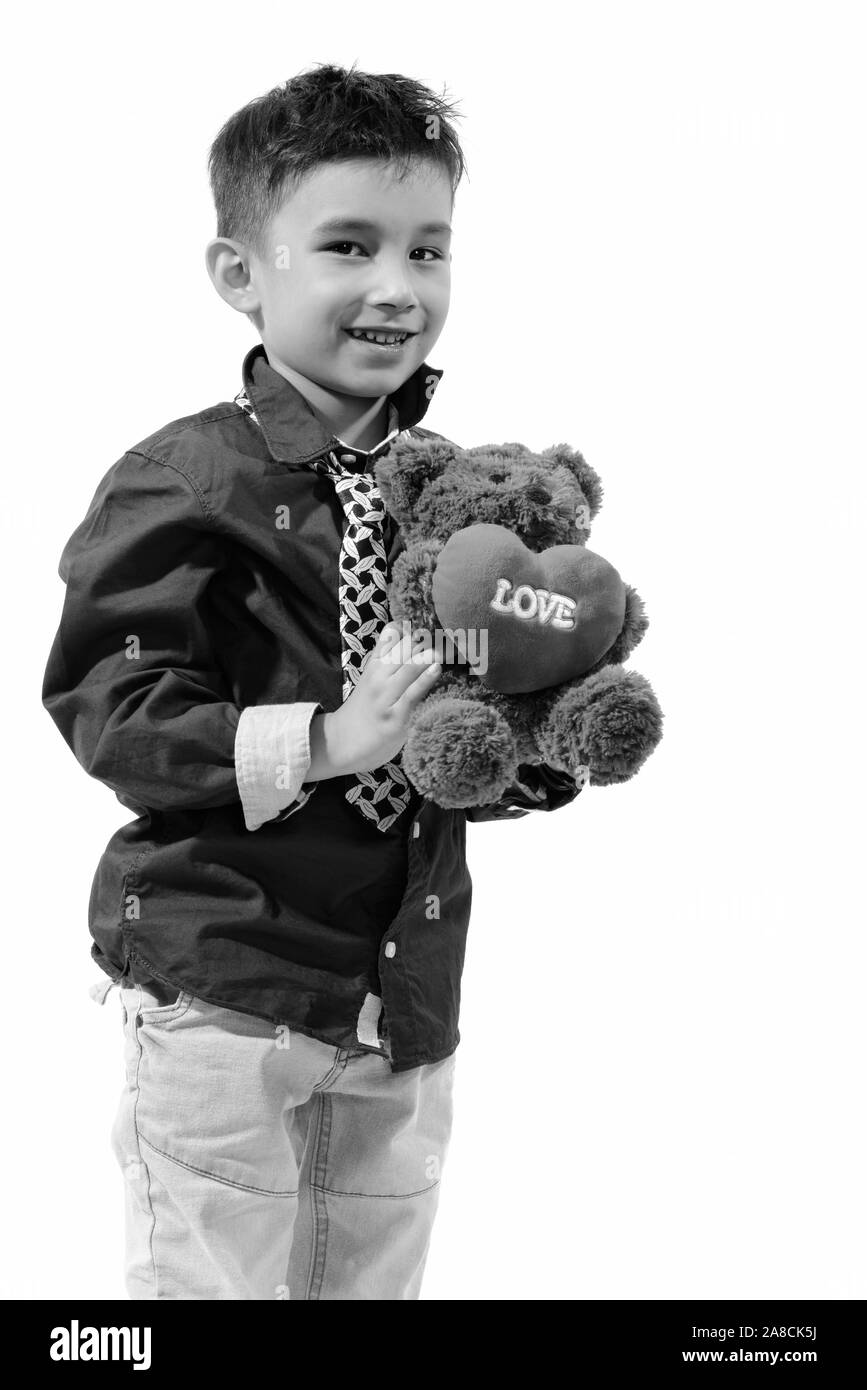 Studio shot of cute happy boy smiling and holding teddy bear with heart and love sign Stock Photo