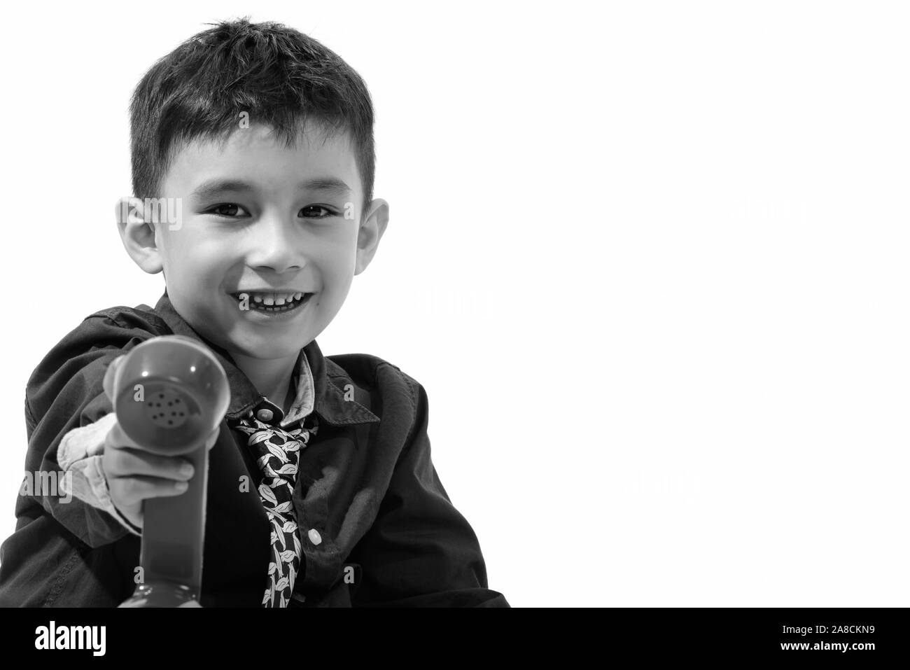 Studio shot of cute happy boy smiling and giving old telephone Stock Photo
