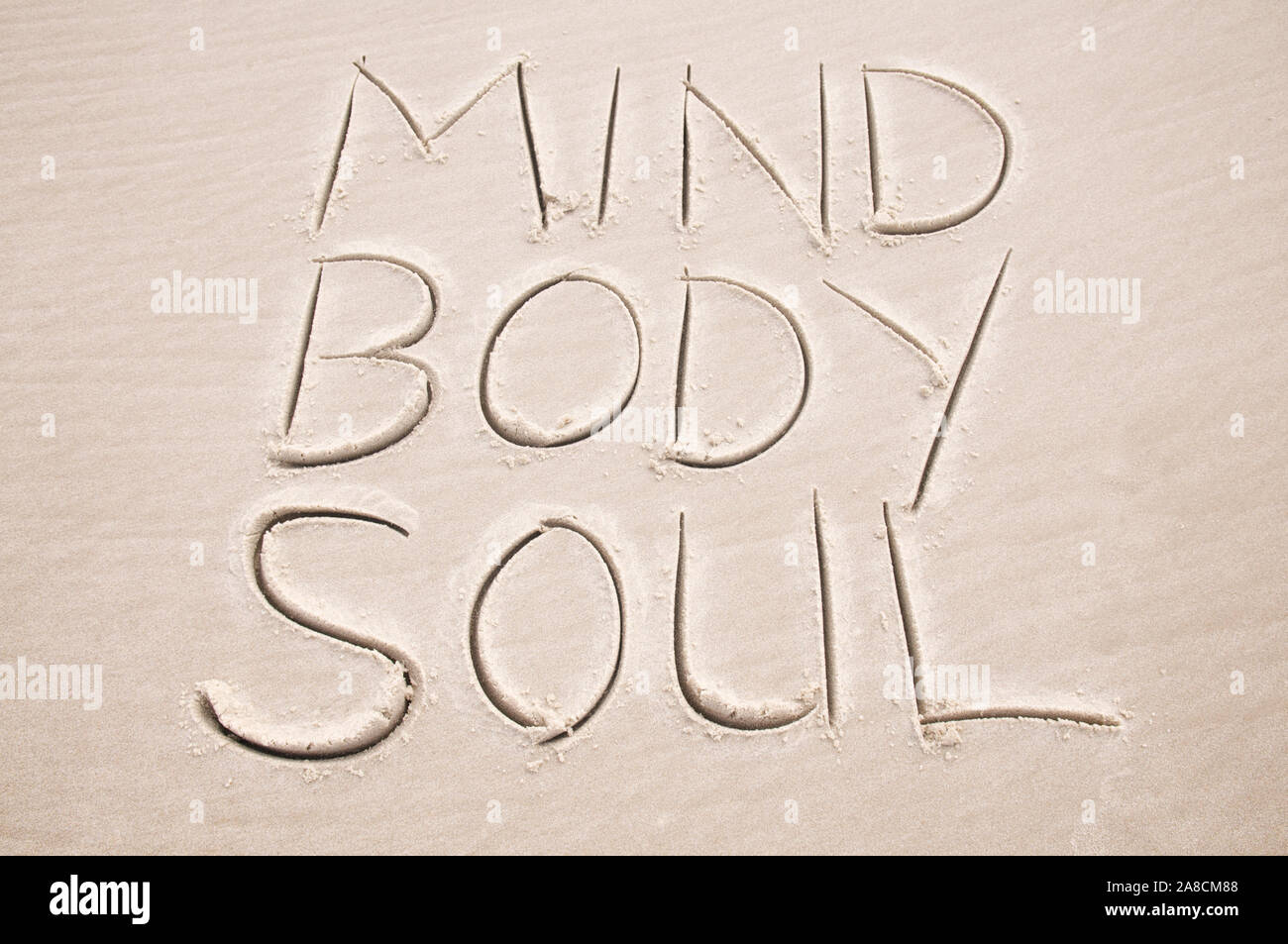 Holistic healing message handwritten in smooth sand spelling out Mind