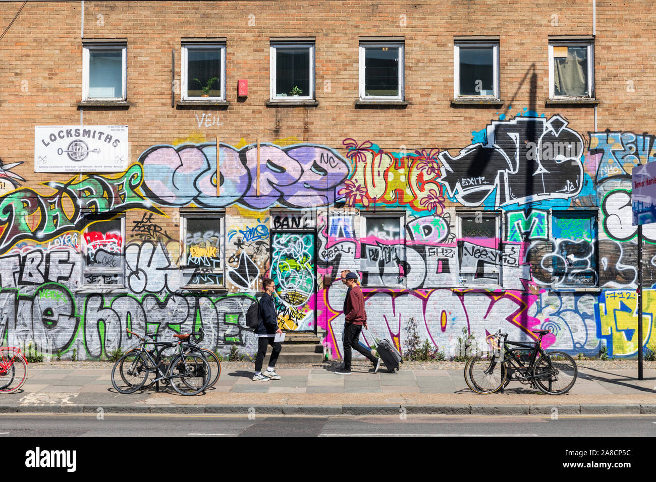 Pedestrians walk past street art in Shoreditch, east London, England, UK. Stock Photo