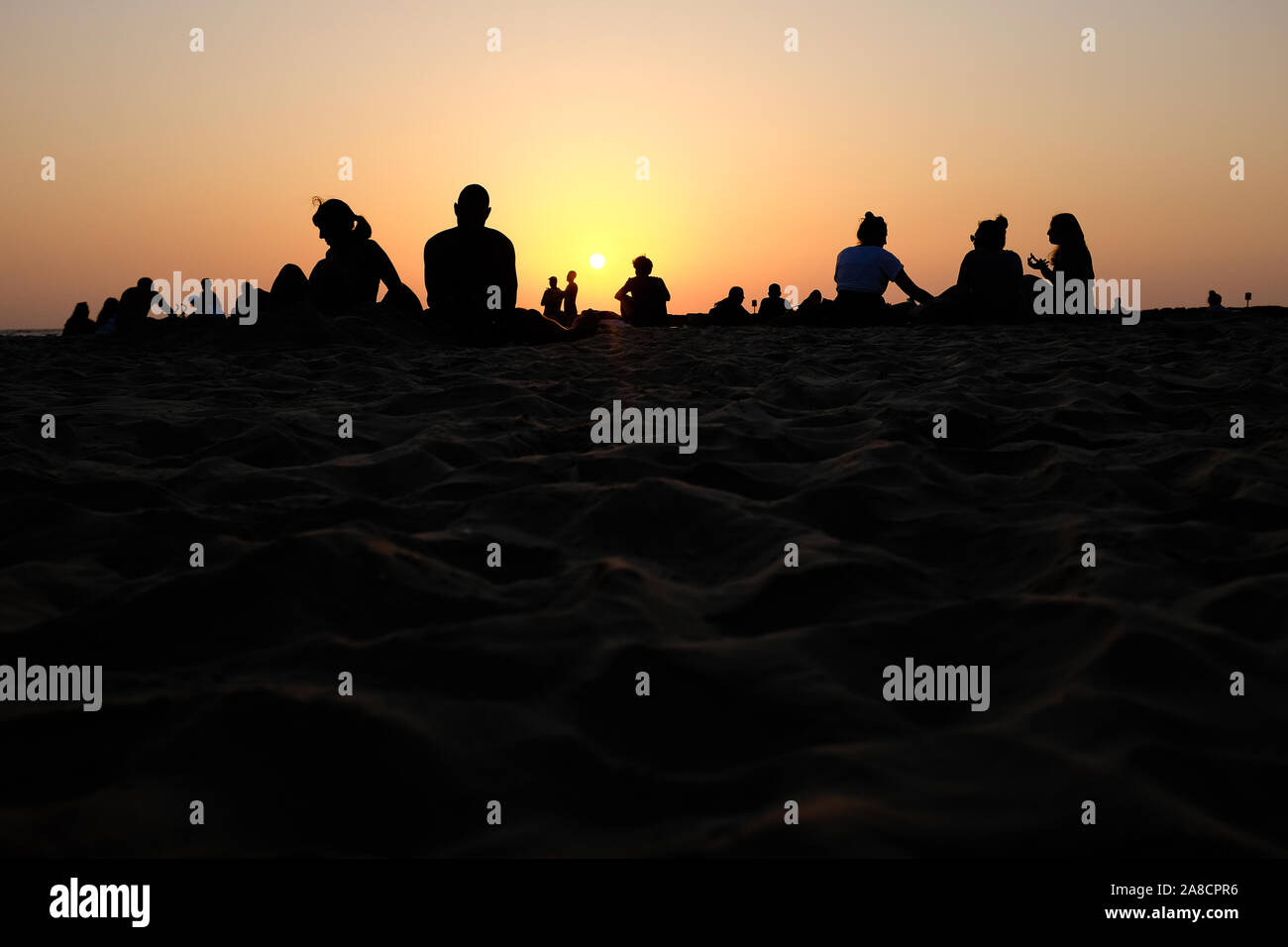 Silhouettes of people on beach at sunset Stock Photo