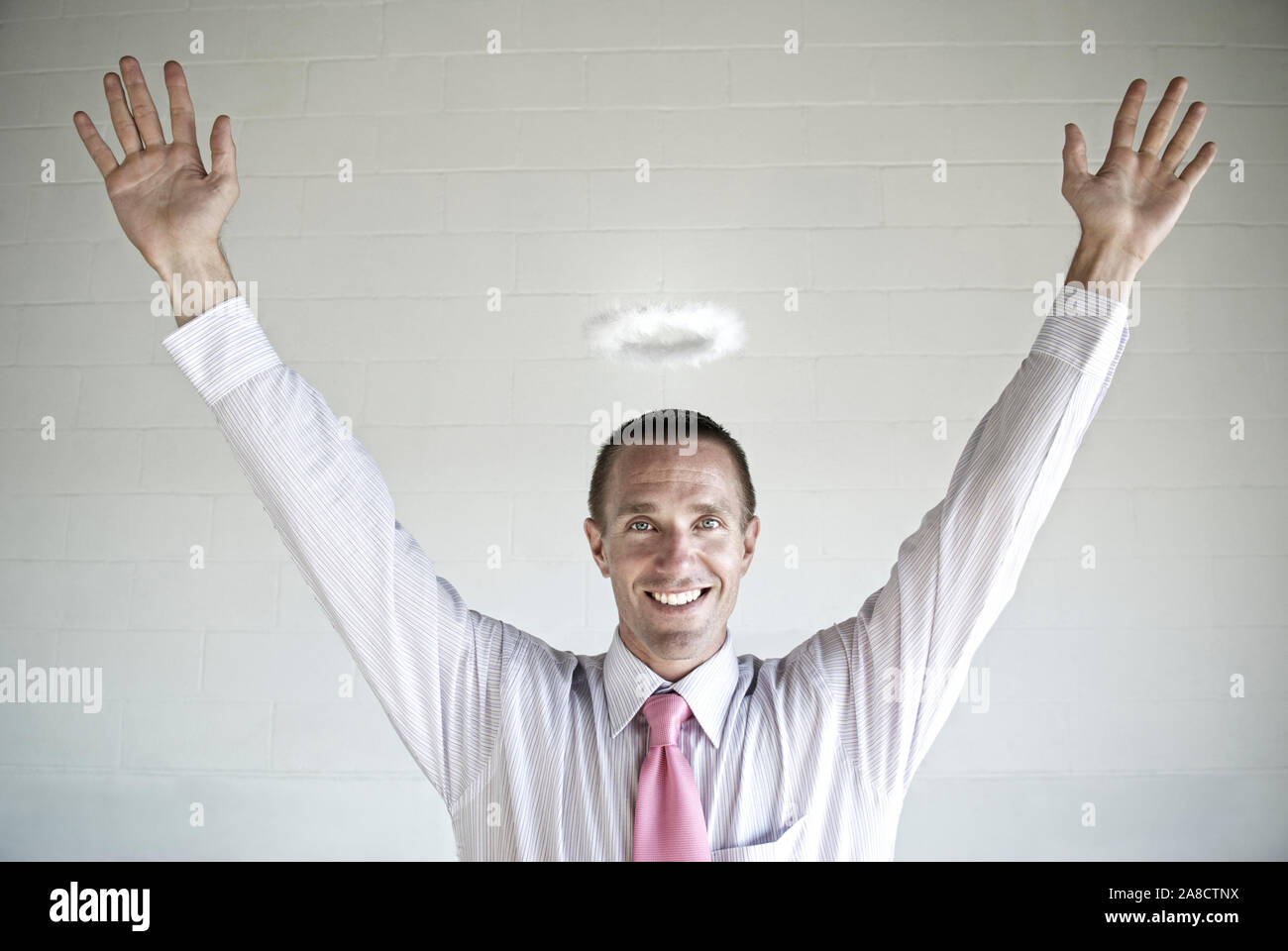 Happy angel investor businessman raising his hands with a smile against a grungy startup block wall Stock Photo