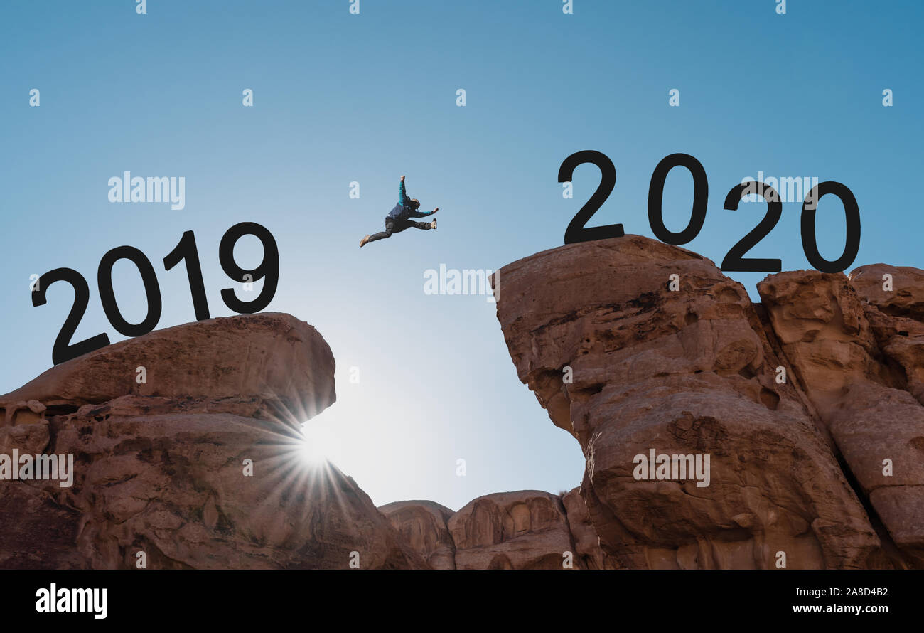 Silhouette a man jumping across cliff from 2019 to 2020 Stock Photo