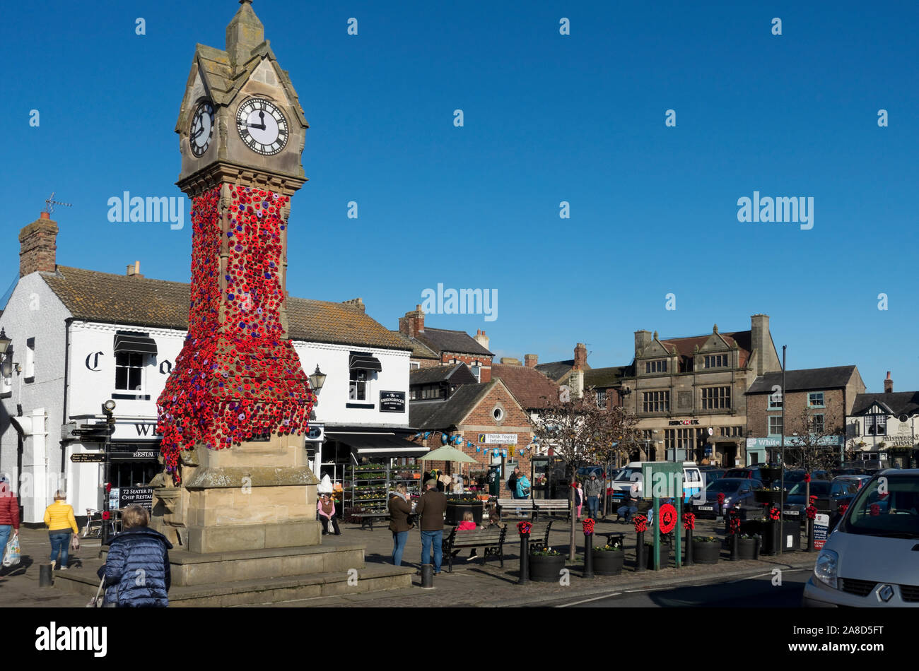 Remembrance Day poppy knitted poppies yarn bombing on clock tower Market Square Thirsk North Yorkshire England UK United Kingdom GB Great Britain Stock Photo