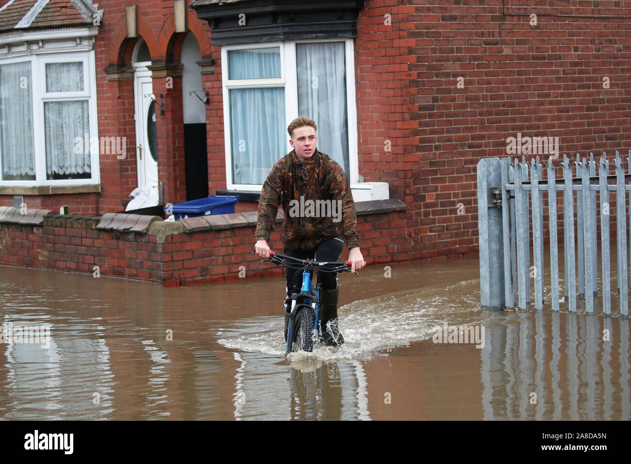 A teenager rides his bike through floodwater in Doncaster, Yorkshire, as parts of England endured a month's worth of rain in 24 hours, with scores of people rescued or forced to evacuate their homes, others stranded overnight in a shopping centre, and travel plans thrown into chaos. Stock Photo