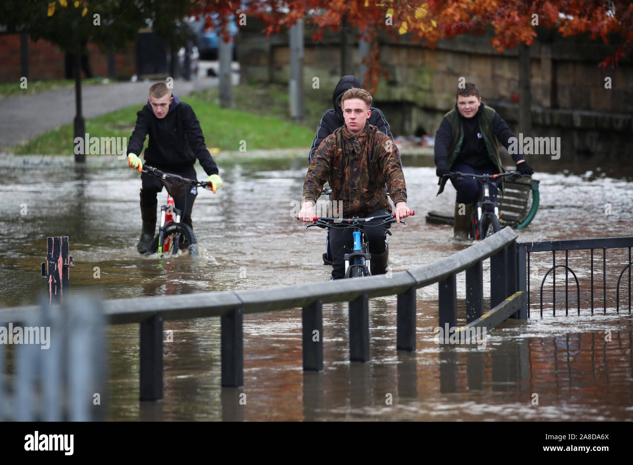 Teenagers ride their bikes through floodwater in Doncaster, Yorkshire, as parts of England endured a month's worth of rain in 24 hours, with scores of people rescued or forced to evacuate their homes, others stranded overnight in a shopping centre, and travel plans thrown into chaos. Stock Photo