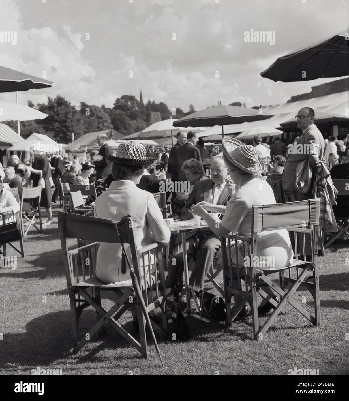 1950s, historical, English garden party, well-dressed visitors having lunch outside at the All England Lawn Tennis Club, at the Wimbledon, South London, England, UK, a famous Tennis Championships founded in 1877. Stock Photo