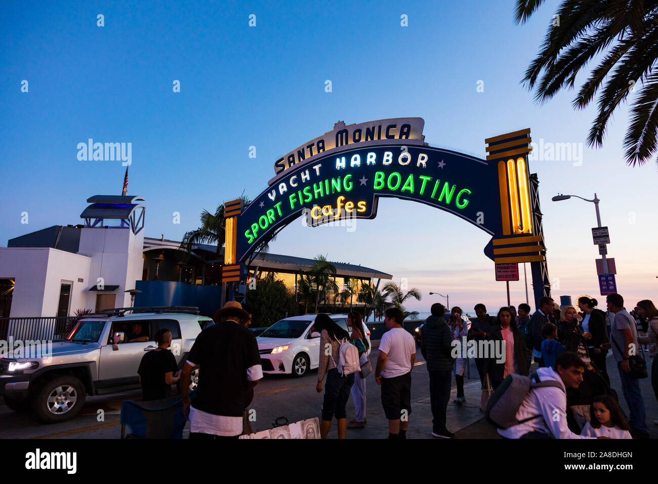 Tourists gather at the entrance sign to Santa Monica pier. Yacht harbor, sport fishing,boating and cafes.  Los Angeles County, California, United Stat Stock Photo
