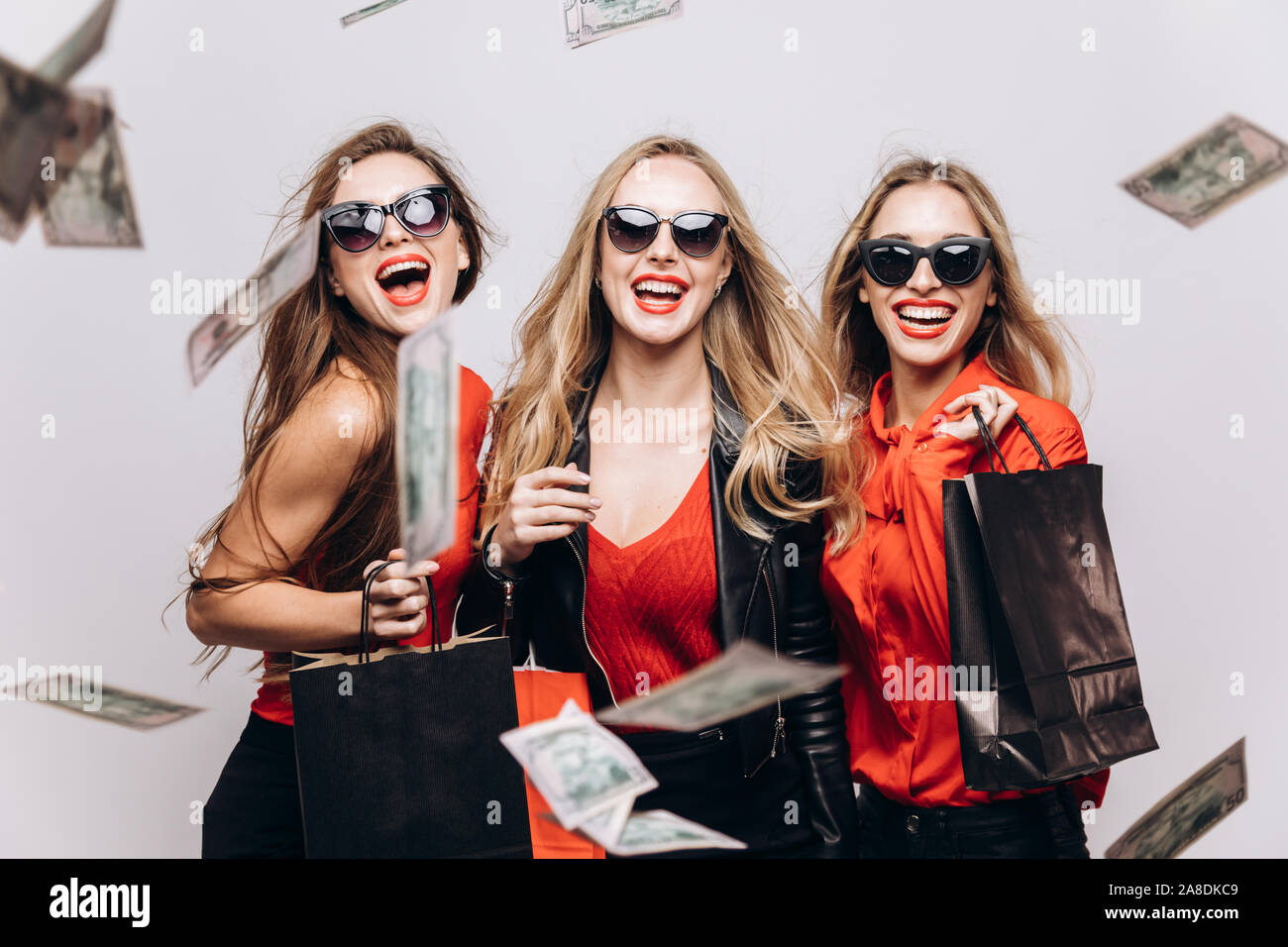 Young female shopping mates in red and black squandering money isolated white background Stock Photo