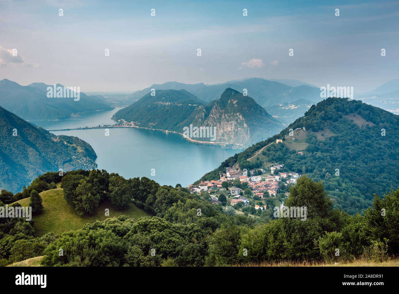 The village of Bre, Lugano Lake , and famous mountains of this area. Beautiful aerial view of a lake, Swiss village and surrounding high mountais. Stock Photo