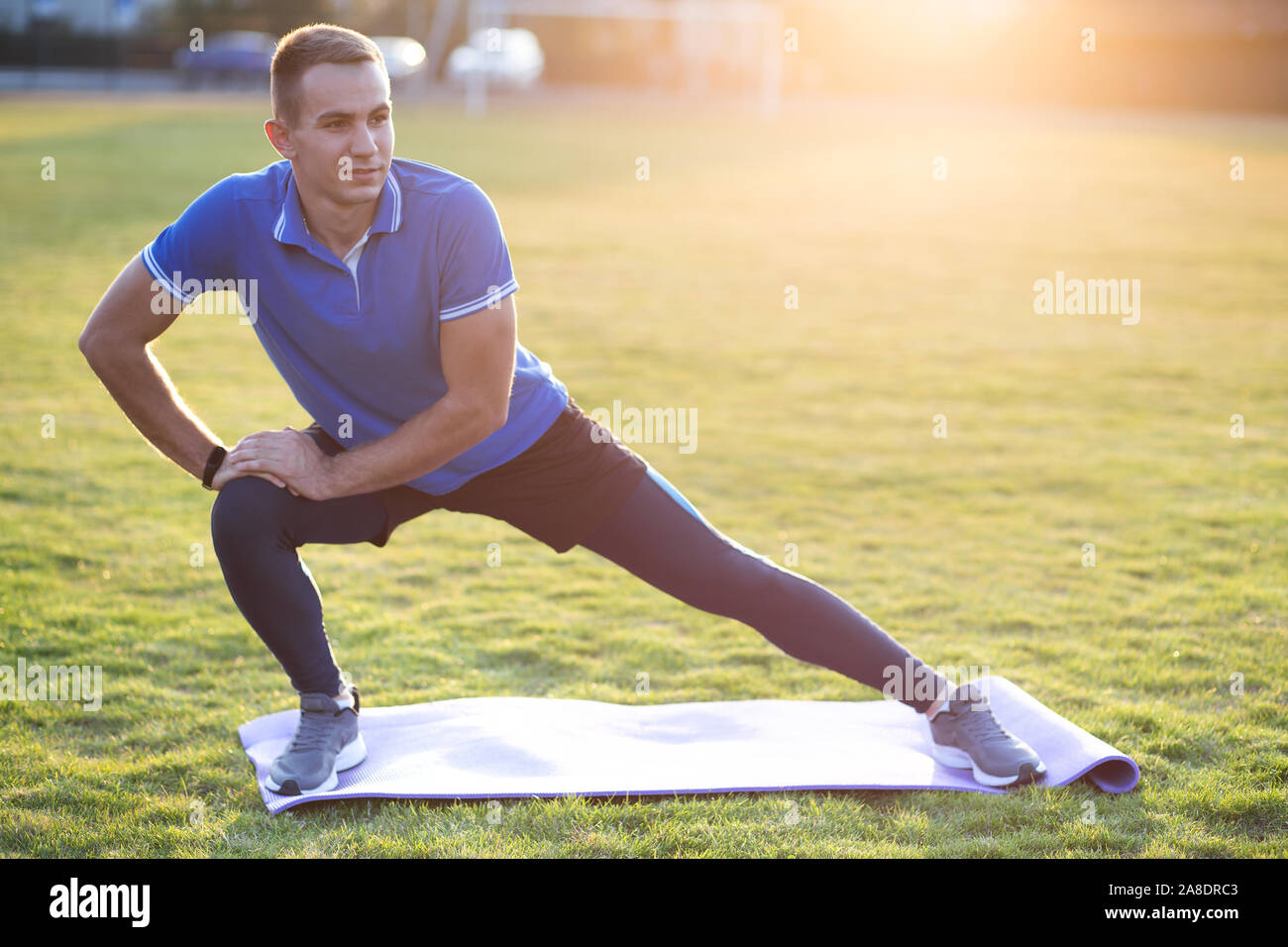 Young sportive man doing stretching exercises before running in morning