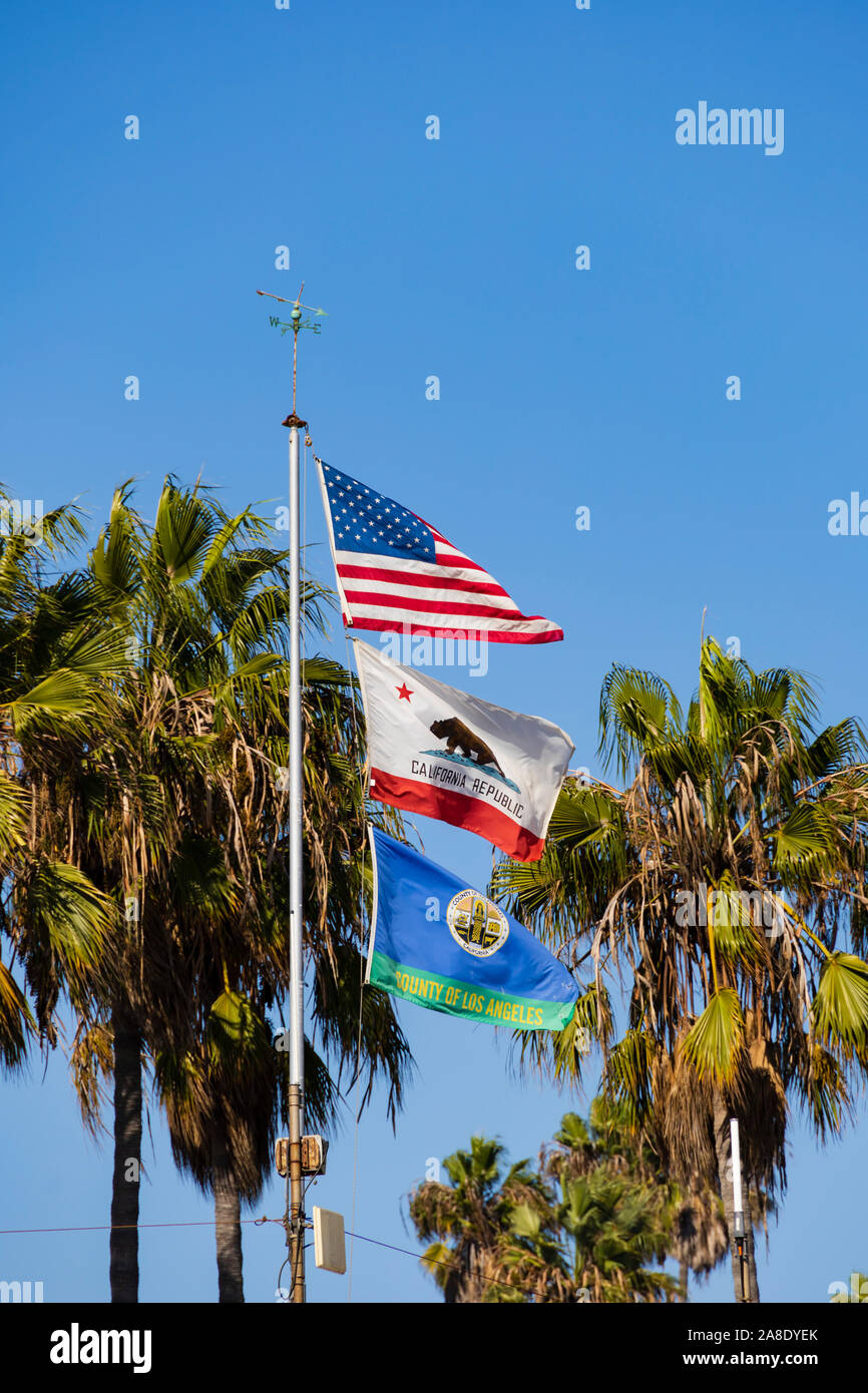 National flag, state flag and County Flag flying together over the Lifeguard office building, Santa Monica, Los Angeles County, California, United Sta Stock Photo