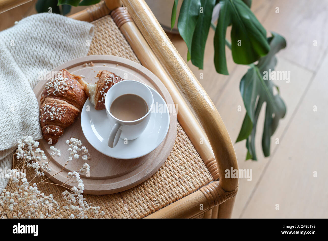 https://c8.alamy.com/comp/2A8E1Y8/a-cup-of-coffee-and-croissant-on-a-wicker-table-and-monstera-flower-on-the-background-2A8E1Y8.jpg