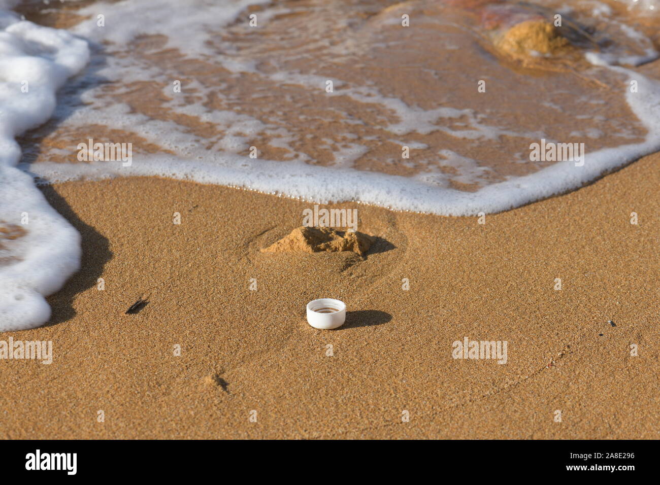 Plastic polution on sand beach with sea in view Stock Photo