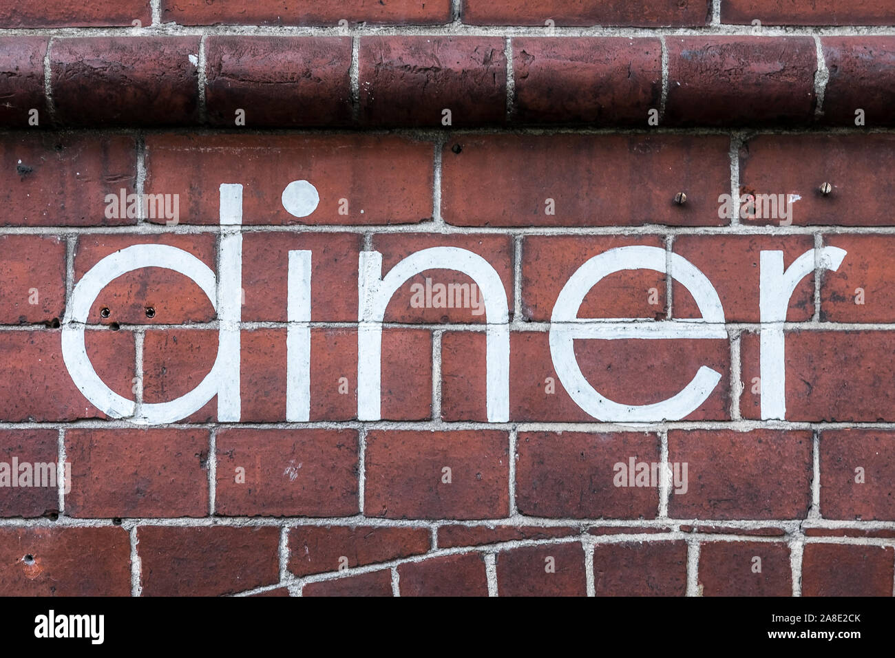The word 'diner' written in neat paint, on a brick wall. Stock Photo