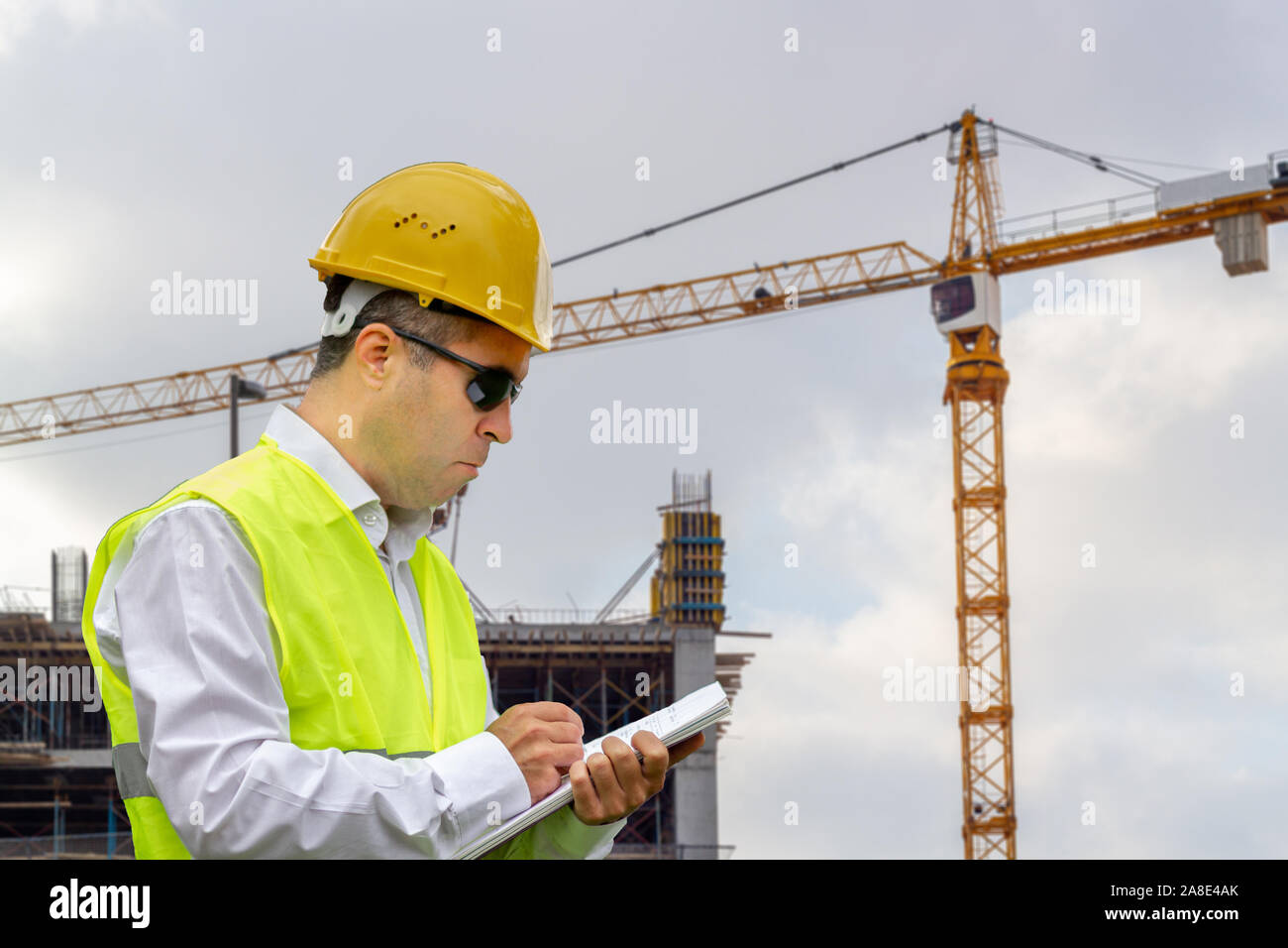 Construction worker man with safety helmet and vest works at construction site. Concept of people working in industrial field Stock Photo