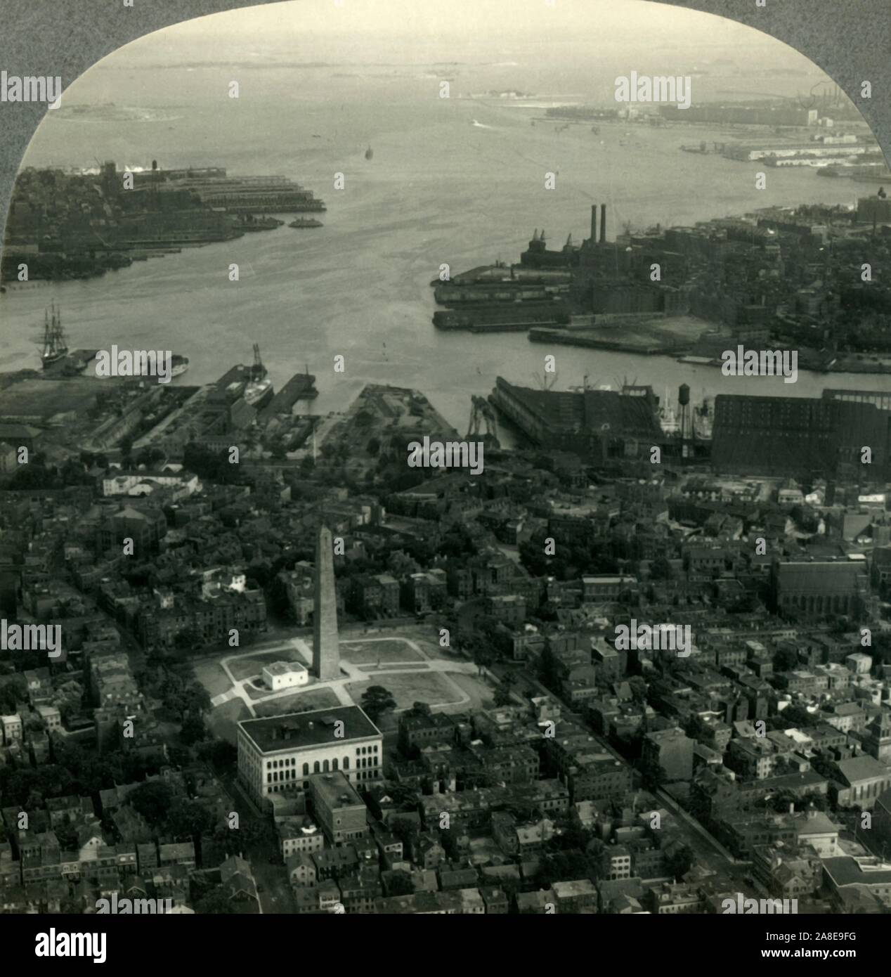 'Bunker Hill Monument and Boston Harbor from the Air, Boston, Mass.', c1930s. Memorial for the Battle of Bunker Hill fought during the American Revolutionary War in Charlestown, laid out in 1629 by engineer Thomas Graves. Boston Hrbour is a a major shipping port in the northeastern United States. From &quot;Tour of the World&quot;. [Keystone View Company, Meadville, Pa., New York, Chicago, London] Stock Photo