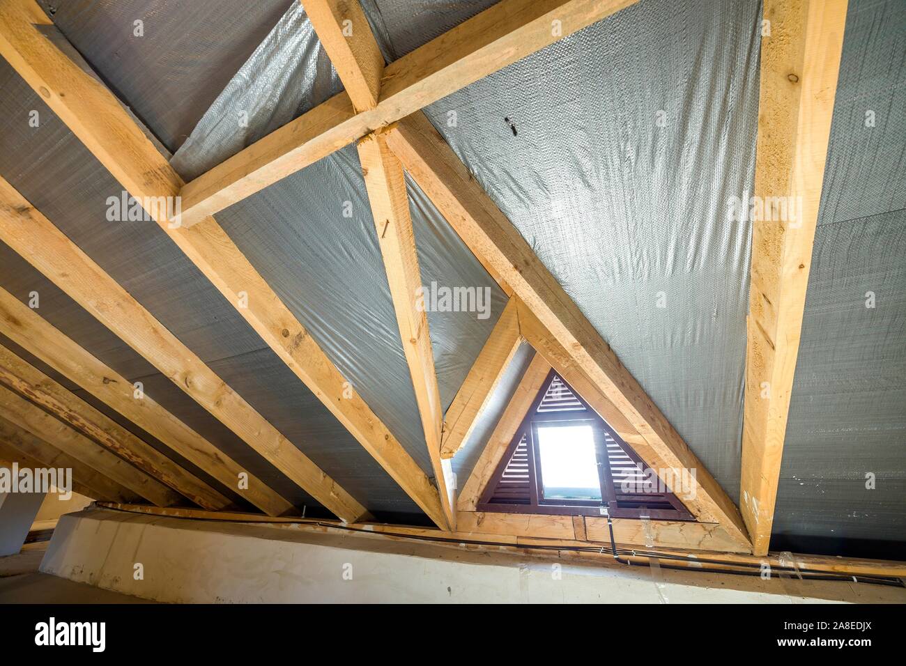 Attic of a building with wooden beams of a roof structure and a small