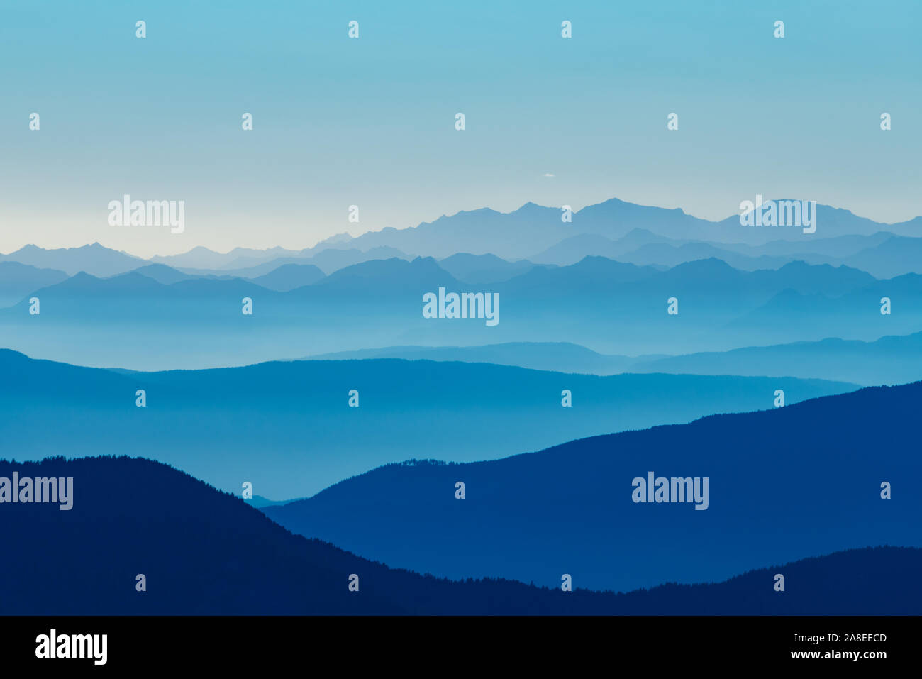 Mountain ranges of the Alps in the horizon under a blue mist Stock Photo