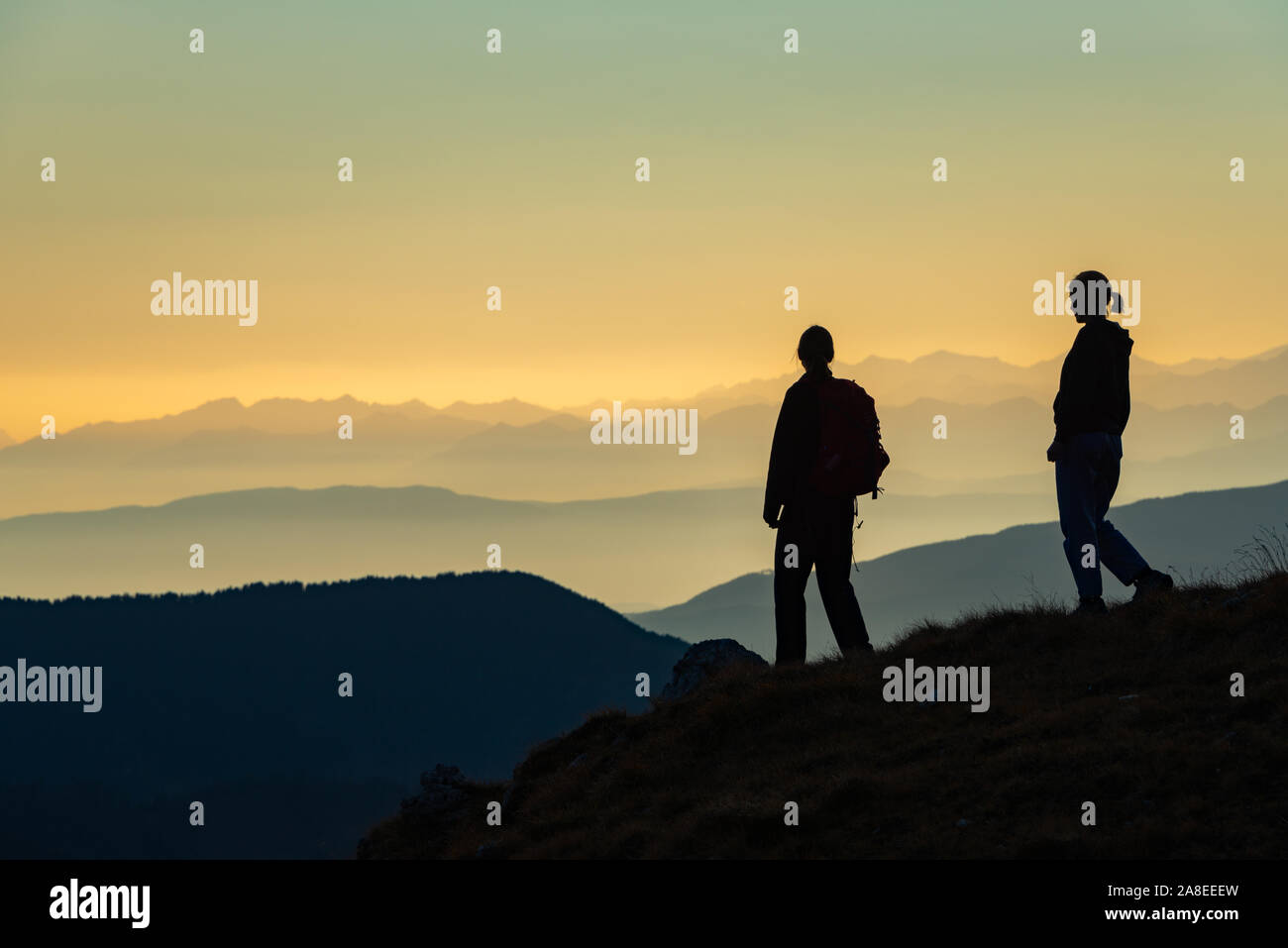 Silhouette of female trekkers, mother and daughter, in the Dolomites, withe Italian Alps in the horizon Stock Photo