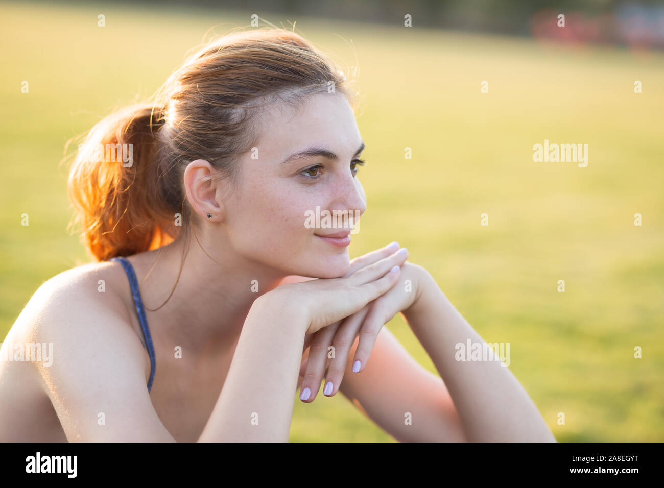 Close up portrait of cheerful smiling young girl with freckles on her face outdoors in sunny summer day. Human expressions and emotions concept. Stock Photo