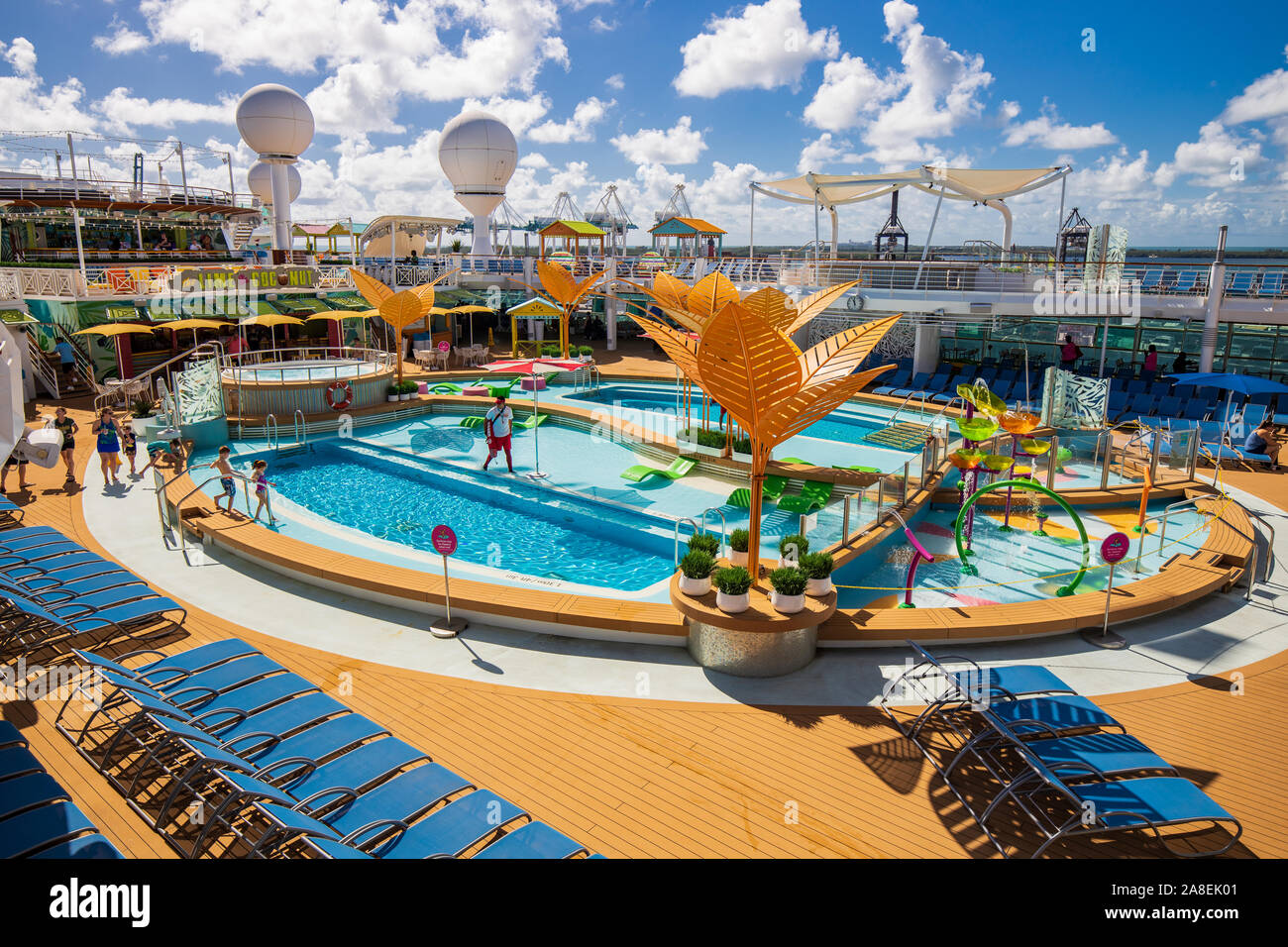 The top of a Royal Caribbean cruise ship with a balcony looking down over a pool with people and lounge chairs. Stock Photo