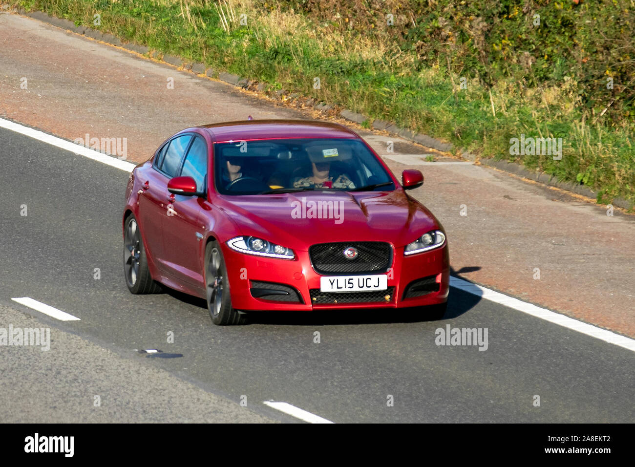 2015 red Jaguar XF R-Sport D Auto; Vehicular traffic, transport, modern, saloon cars, south-bound on the 3 lane M6 motorway highway. Stock Photo