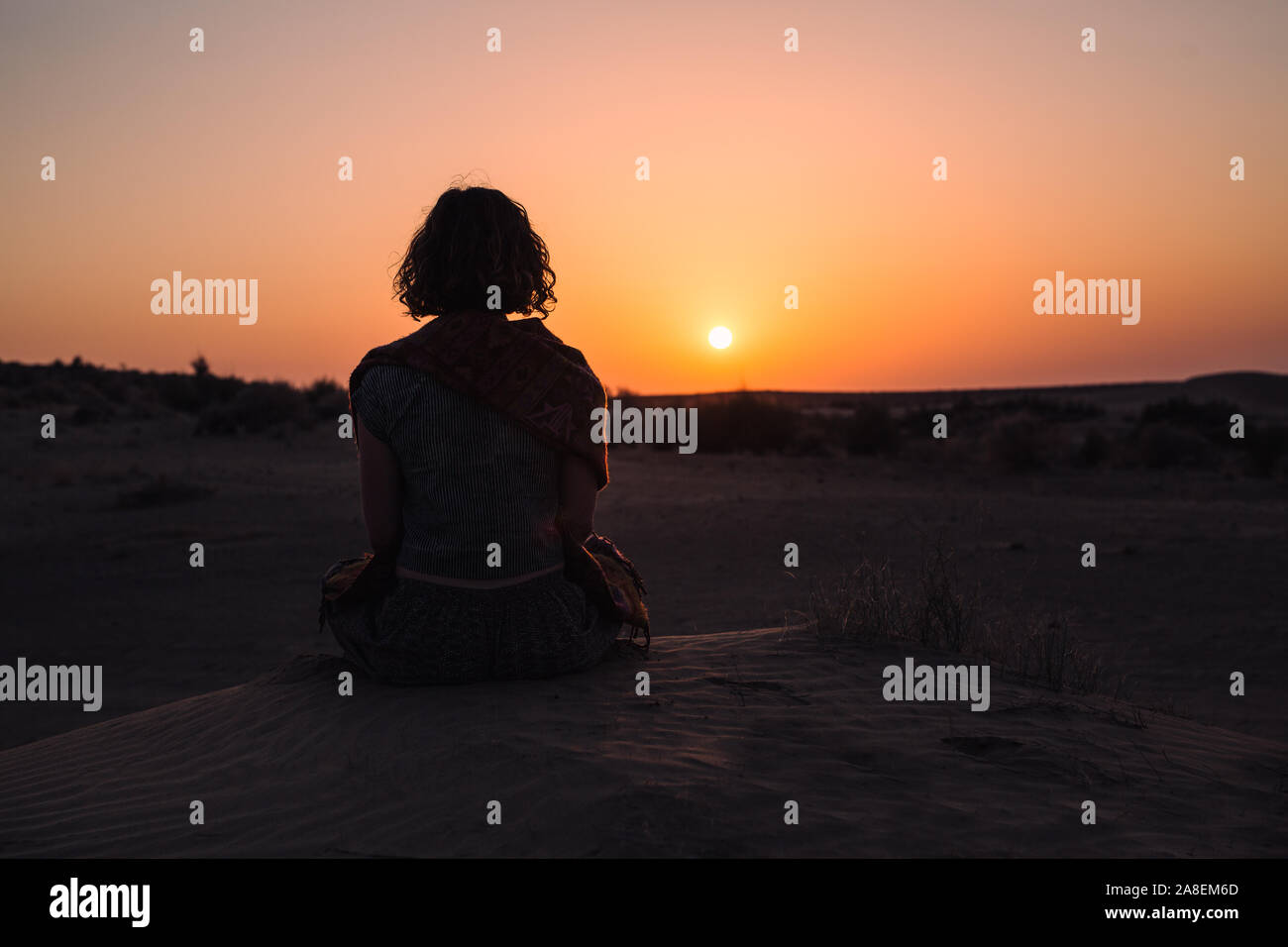 Woman sits to admire the sunset over the dunes, Thar Desert, Jaisalmer, India Stock Photo