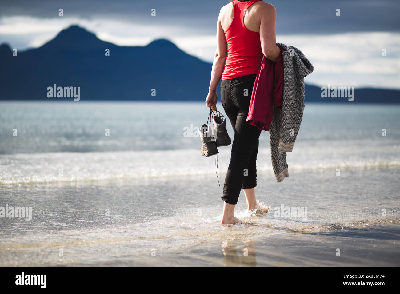 Barefoot walk along the coast of the Isle of Eigg with the Isle of Rum in the background Stock Photo