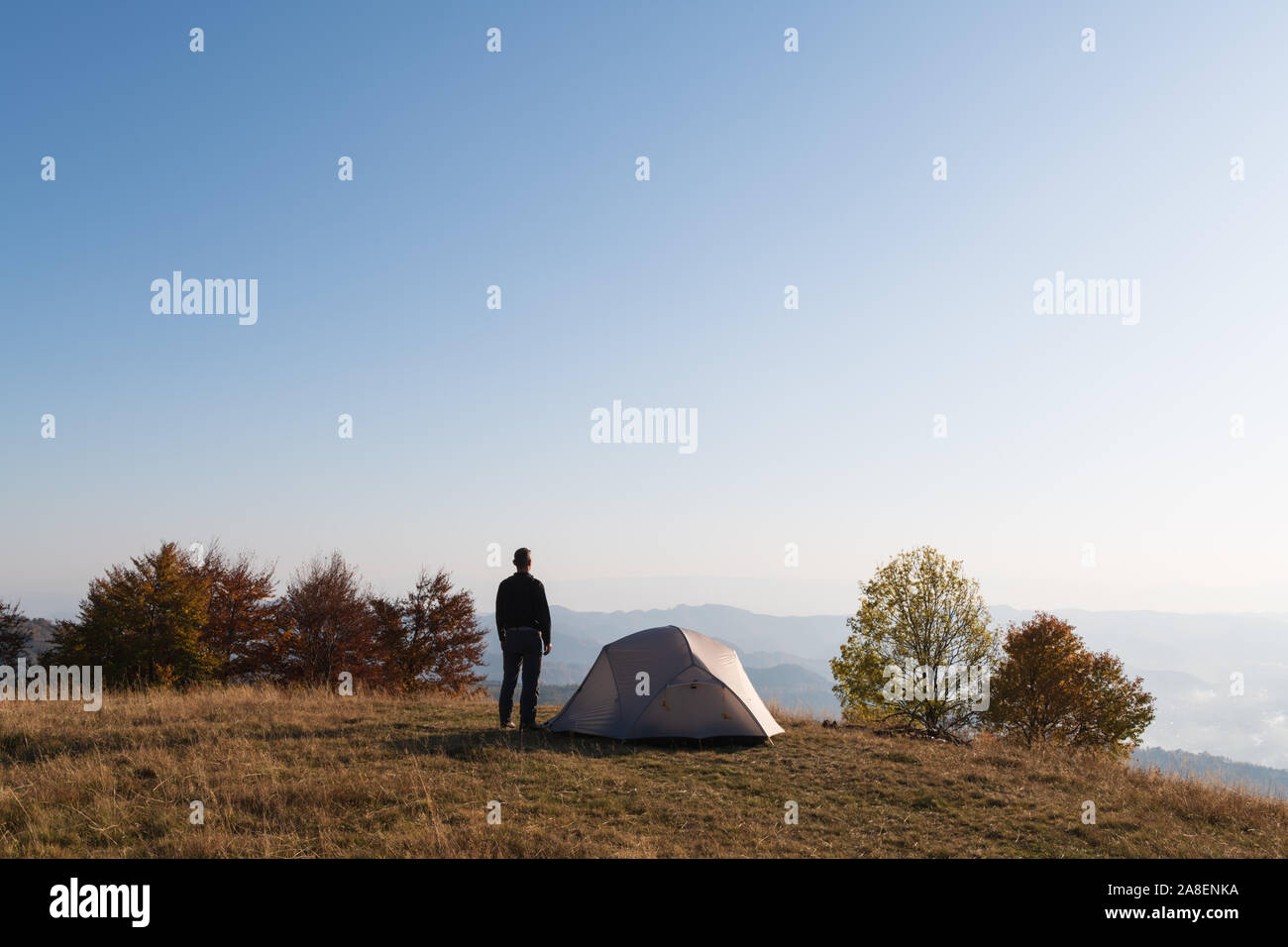 Tourist near his tent against the backdrop of an incredible mountain landscape. Sunny day in highland Stock Photo