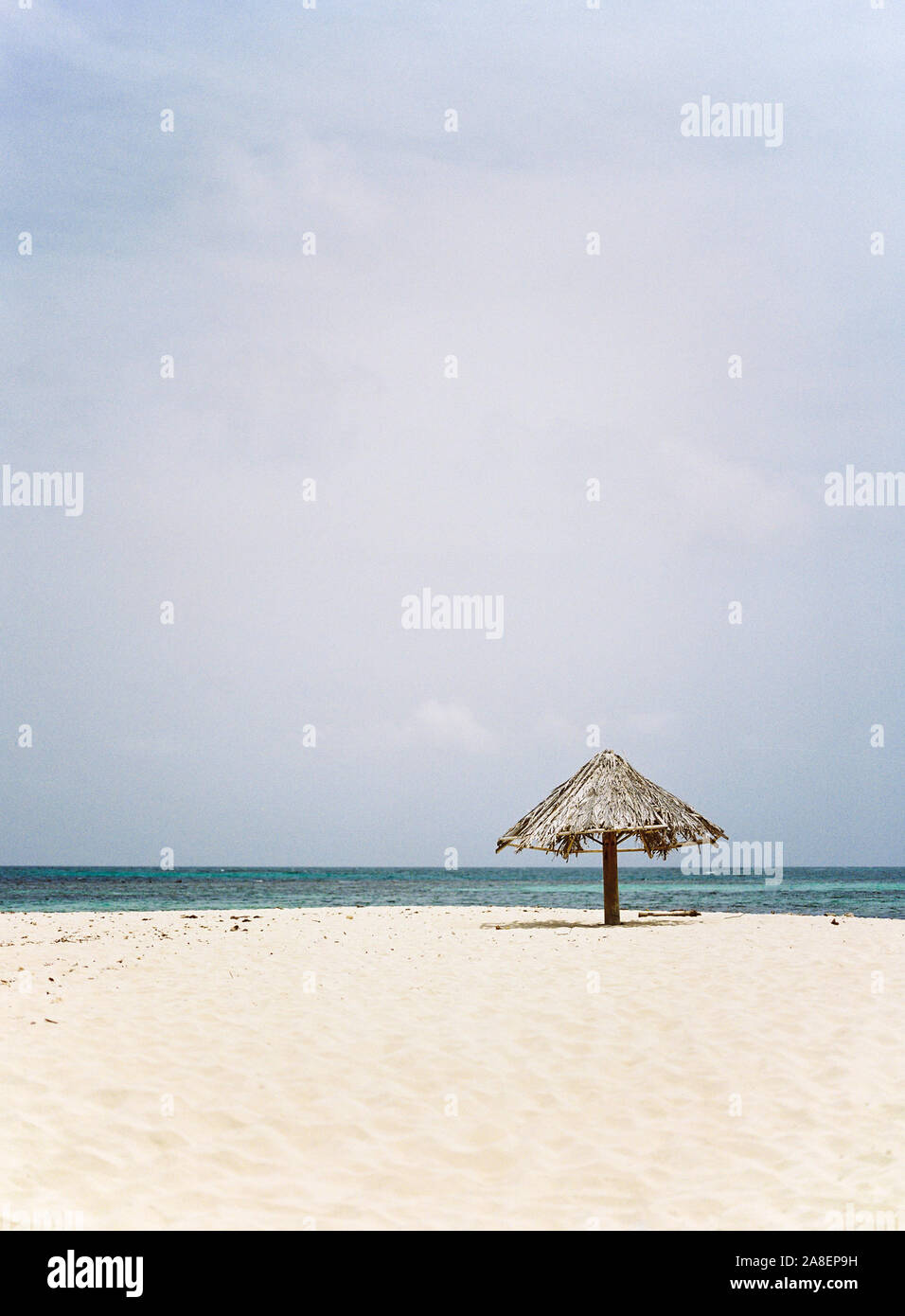 A palm frond umbrella resting on the isolated island beach of Mopion in St. Vincent and the Grenadines. Stock Photo