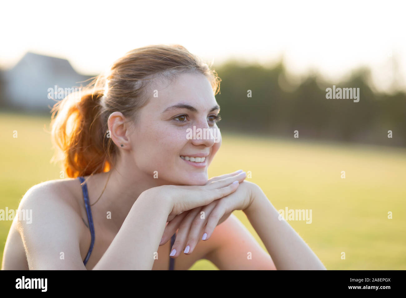 Close up portrait of cheerful smiling young girl with freckles on her face outdoors in sunny summer day. Human expressions and emotions concept. Stock Photo