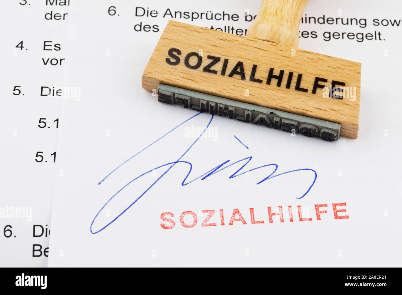 Holzstempel, Formulare im Hintergrund, Aufschrift: Sozialhilfe Stock Photo