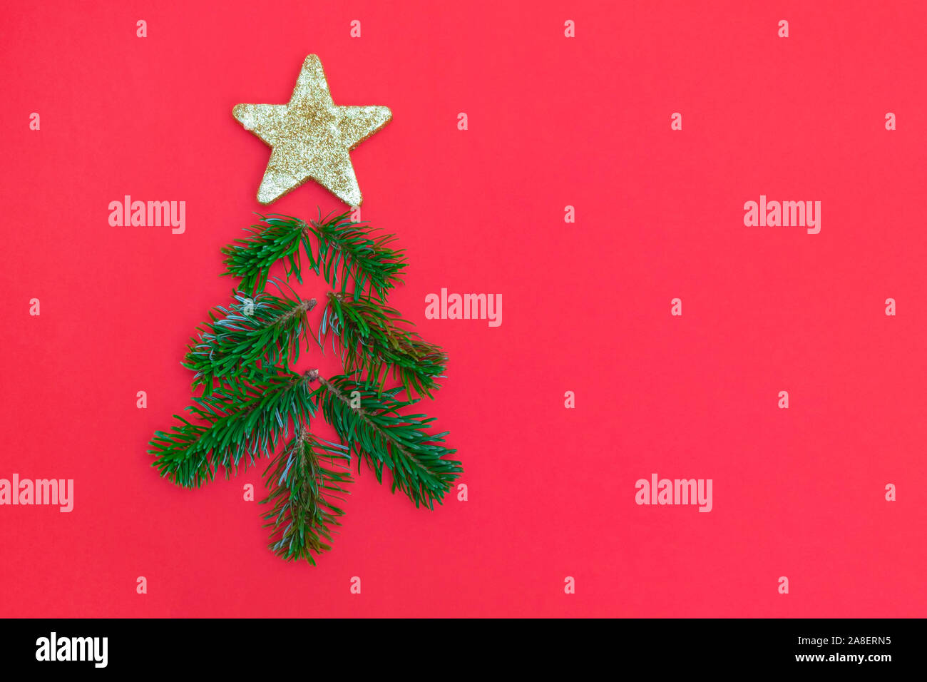 Creative Christmas tree made of pine tree branches and golden star on red background Stock Photo
