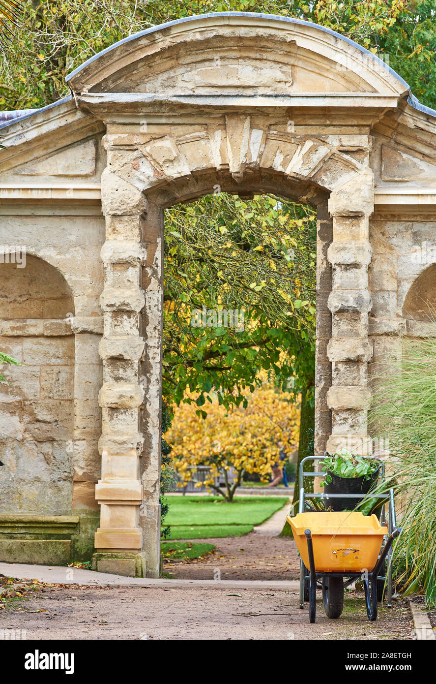 Wheelbarrow parked next to an doorway during late autumn at the botanic garden of the university of Oxford, England. Stock Photo