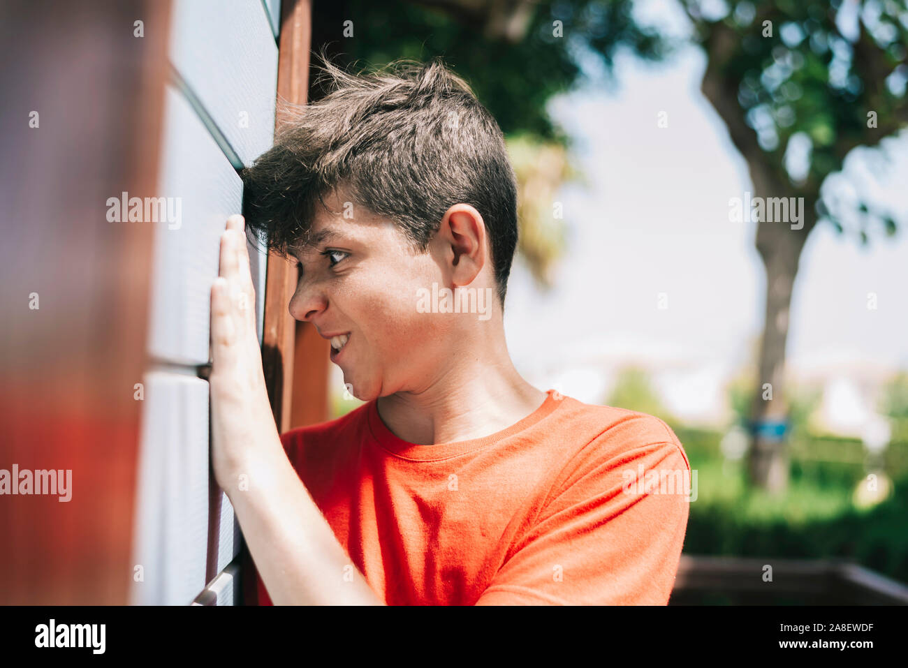 Side view of teenage male grimacing against a outdoors wall Stock Photo